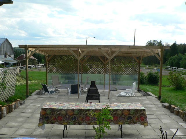 Une terrasse couverte d'une tonnelle ombragée par la vigne vierge et le houblon.